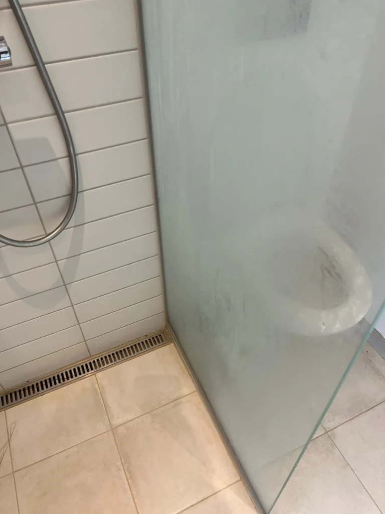 Brusekabine med kalkaflejringer på glas og fliser