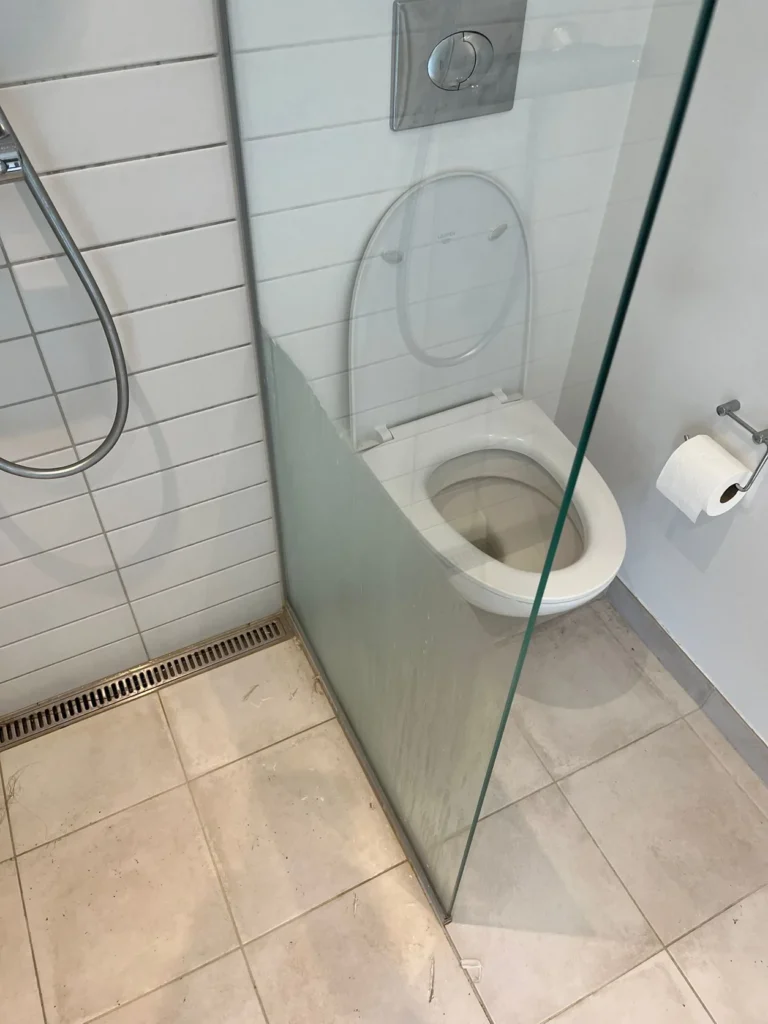 Brusekabine med glasvæg under afkalkning
