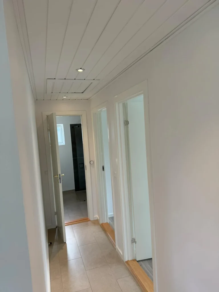 Lyse vægge og loft i en gang med flere døråbninger